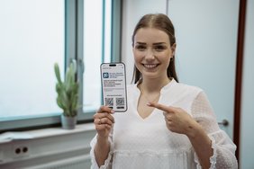 Mitarbeiterin zeigt Flyer der App
