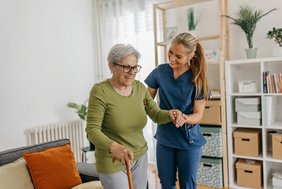 Pflegerin stützt ältere Dame 